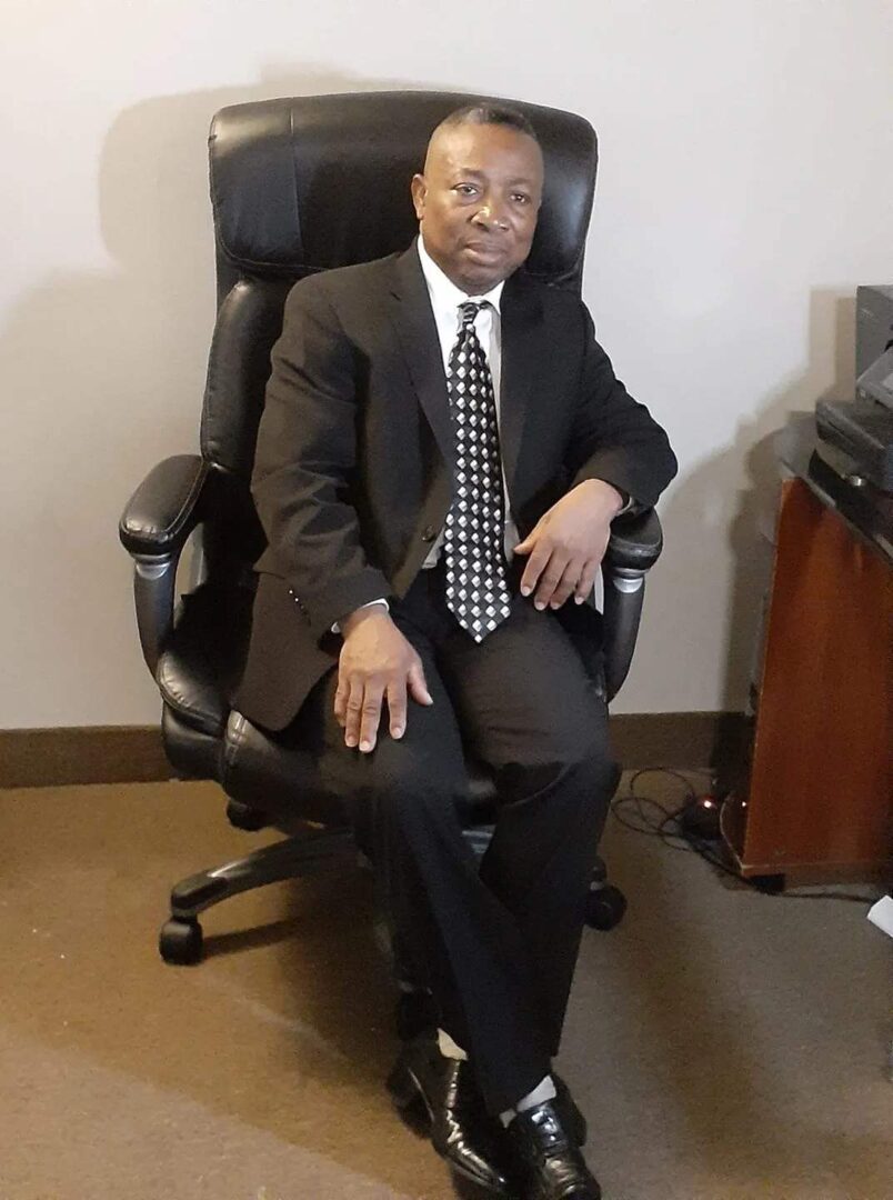 A man in suit and tie sitting on an office chair.